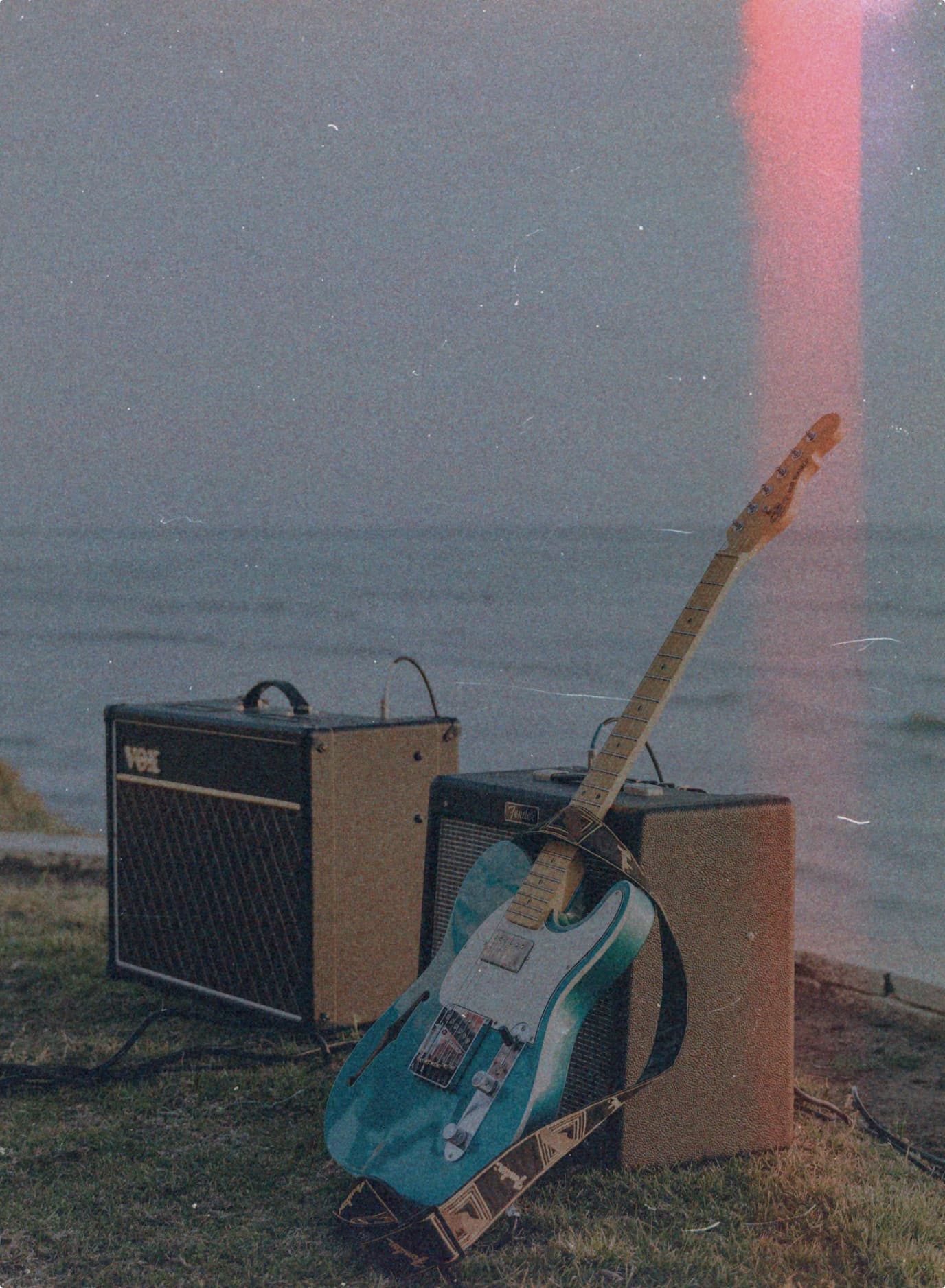 A Telecaster guitar and two amplifiers on the grass by the sea in the north of Spain.