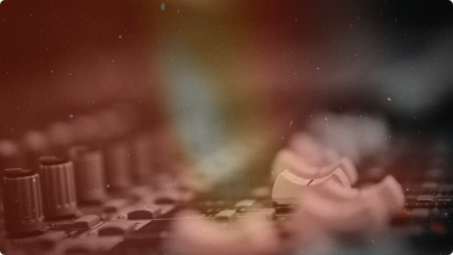 A hand on a mixing desk in warm amber light.