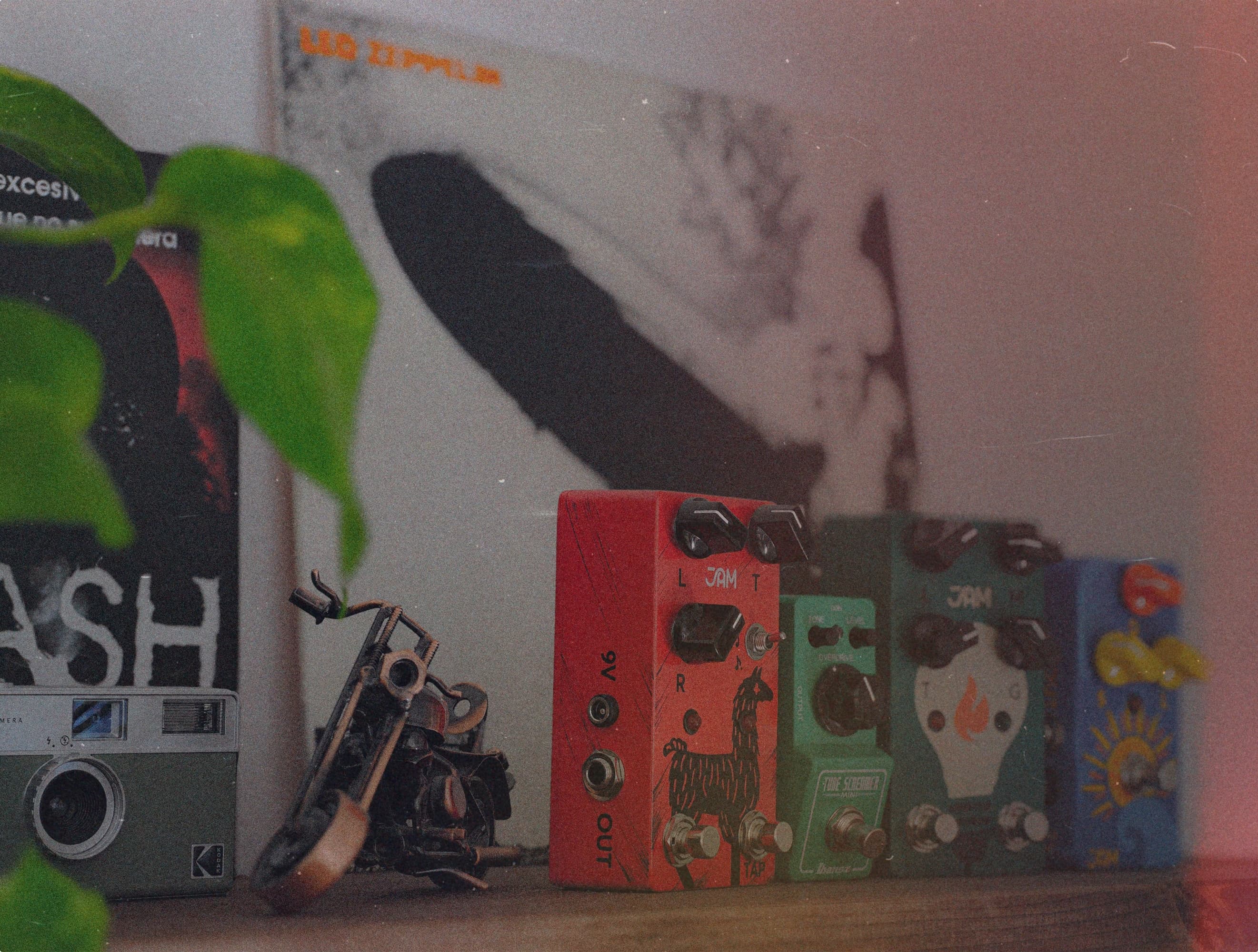 A shelf in the Madrid studio: guitar pedals, a film camera and a motorcycle figurine.