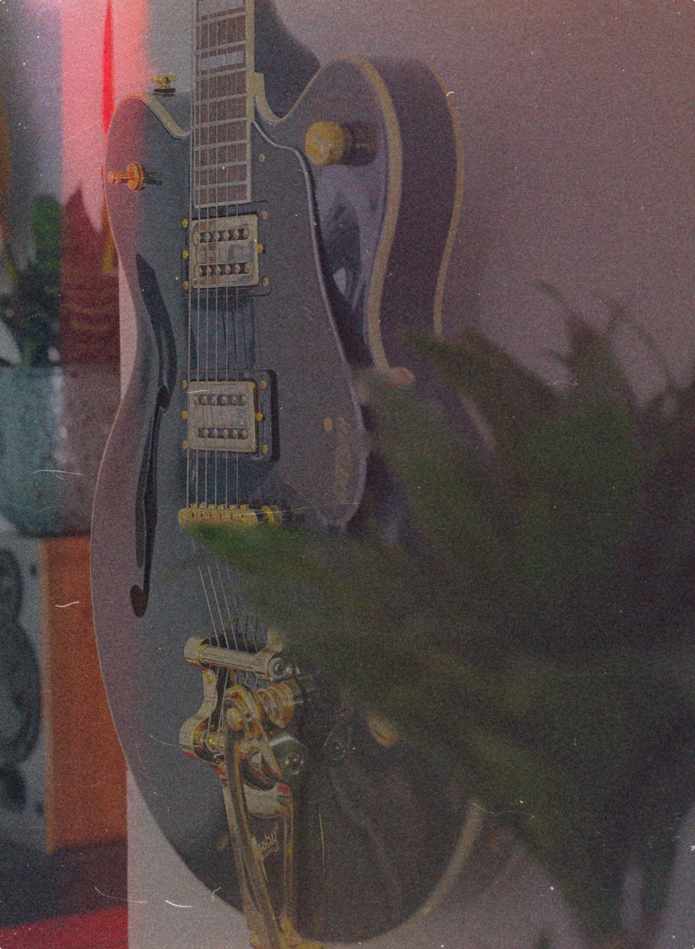 A hollow-body electric guitar under moody red light.